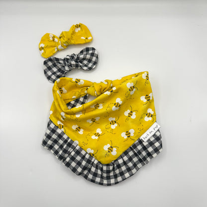 Close-up of bee print yellow gingham ruffle dog bandana laid flat for detail view